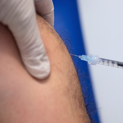 Eine Detailaufnahme zeigt, wie eine Spritze in einen haarigen Oberarm sticht. (Archivbild)