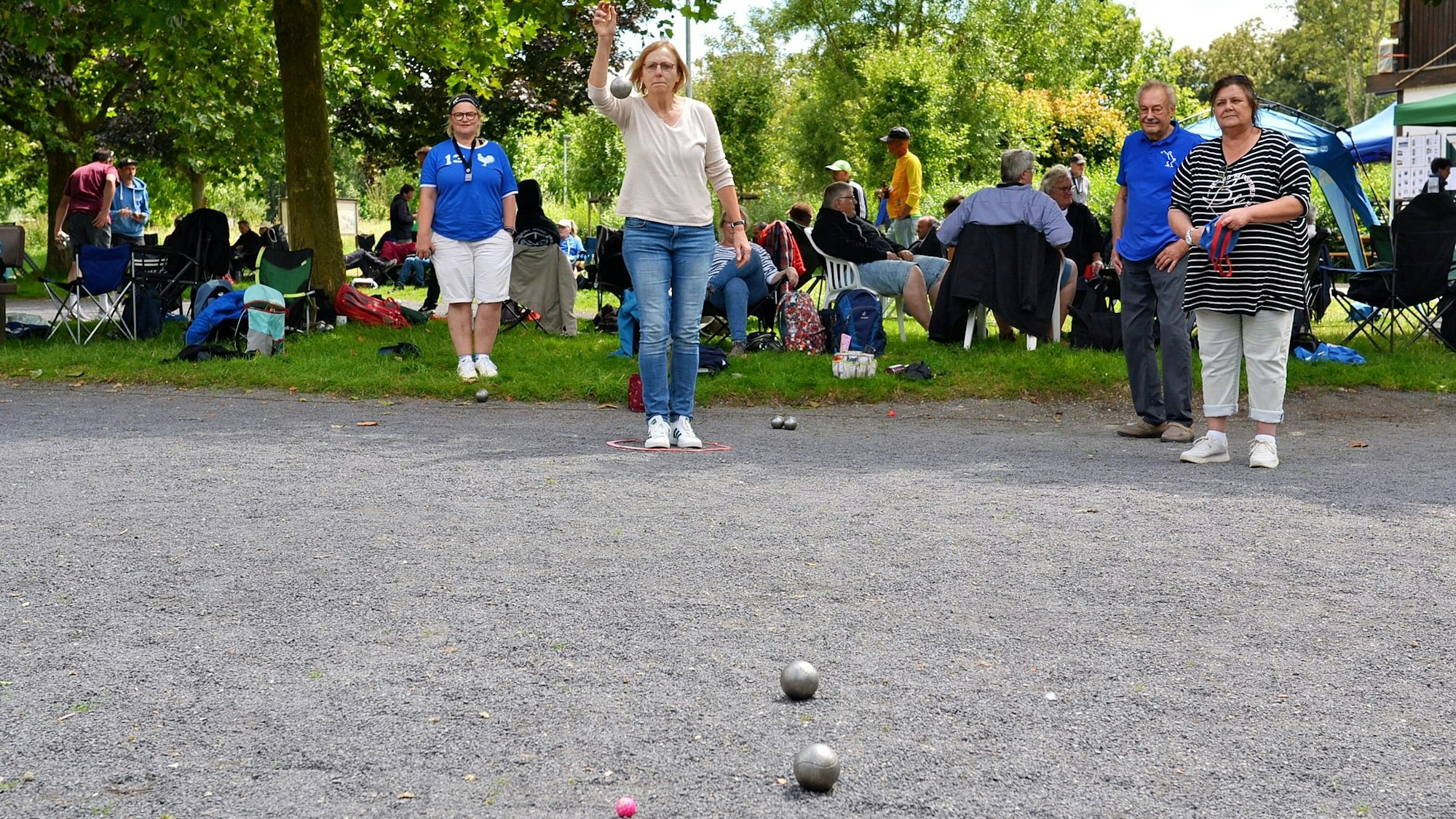 Eine Frau wirft in Euskirchen eine Boule-Kugel. Auf dem Bodenliegen bereits zwei silberne Kugeln und eine kleine, rosafarbene Kugel.