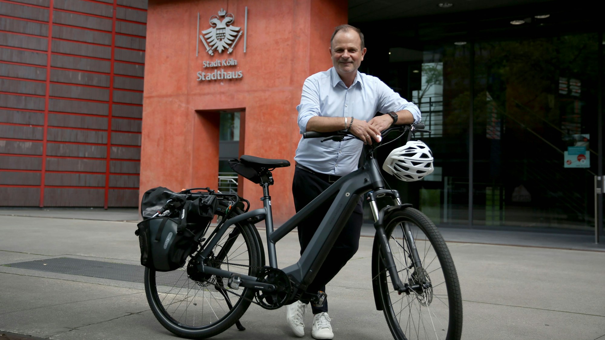 Ralf Mayer vor dem Stadthaus. Der Ordnungsamtsleiter zeigt eines der modernen E-Bikes, mit dem die Mitarbeiter in Köln unterwegs sind.