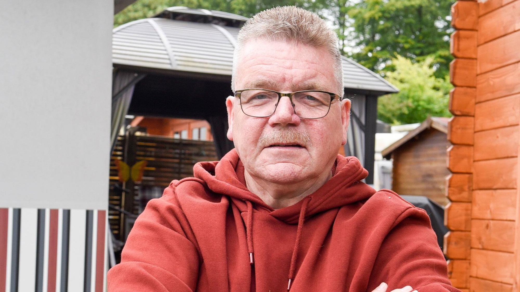Ein Mann steht neben einer Gartenhütte auf einem Campingplatz.