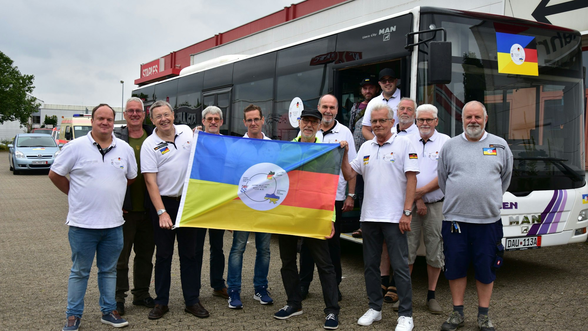 Das Team der freiwilligen Helfer steht mit der deutschen und der ukrainischen Flagge vor einem Bus.