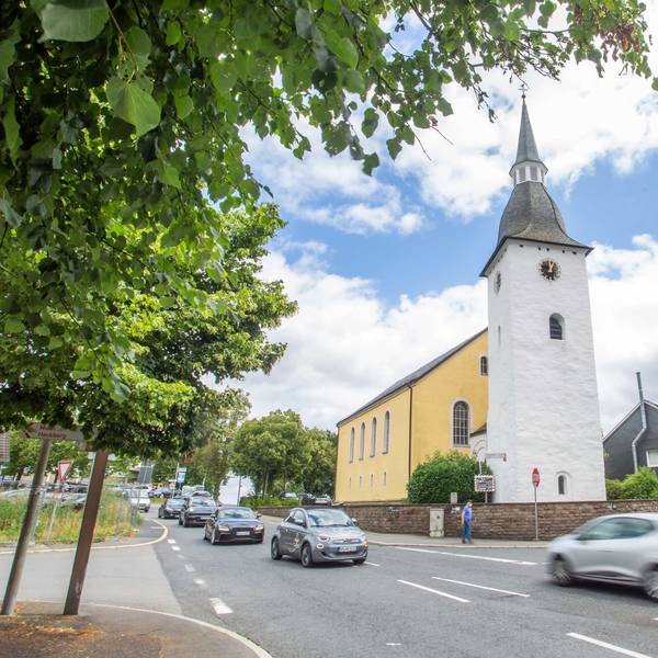 Autos fahren über die Kreuzung, im Hintergrund die evangelische Kirche.