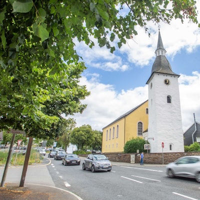 Autos fahren über die Kreuzung, im Hintergrund die evangelische Kirche.