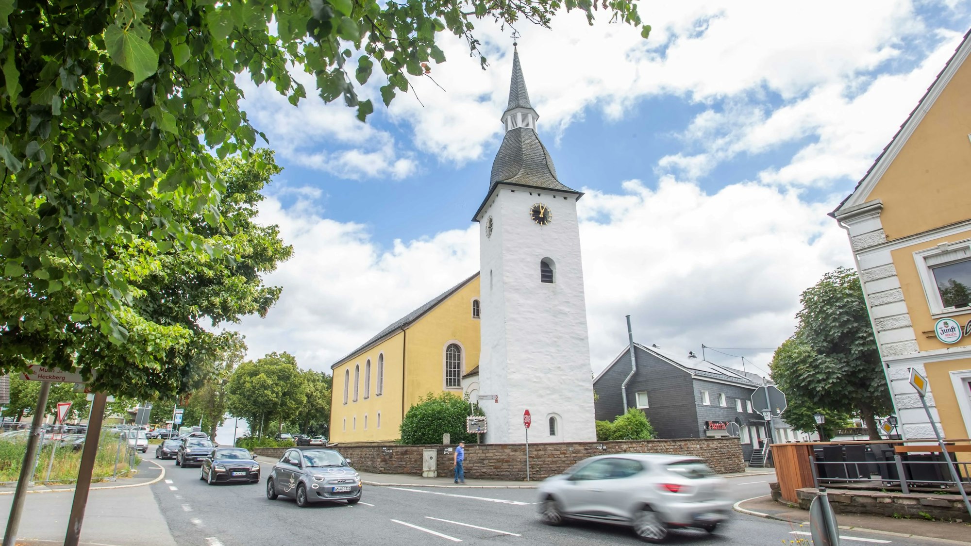 Autos fahren über die Kreuzung, im Hintergrund die evangelische Kirche.