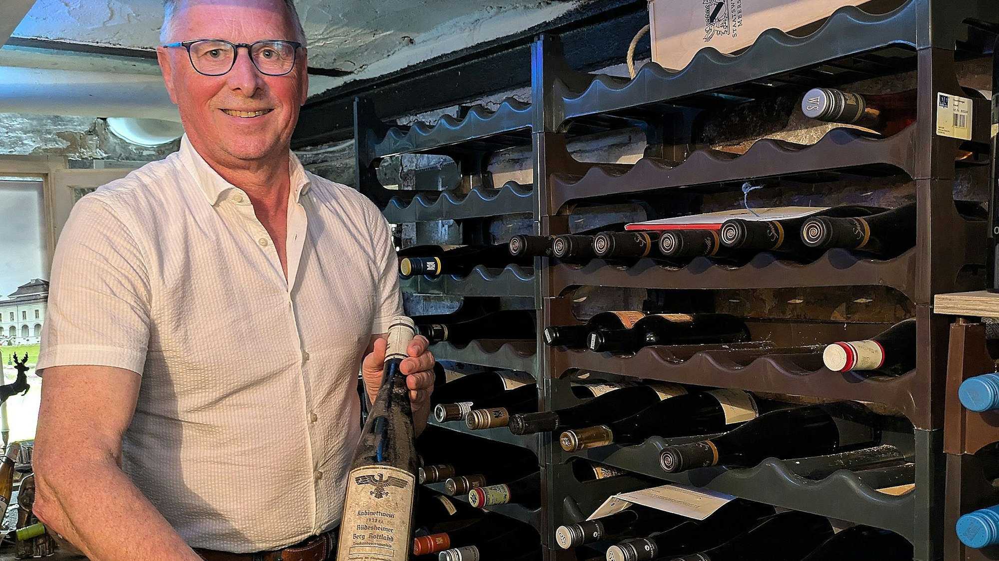 Albert Soehngen präsentiert die historische Weinflasche. Abgefüllt wurde der Riesling vom Rüdesheimer Berg Rottland 1938.