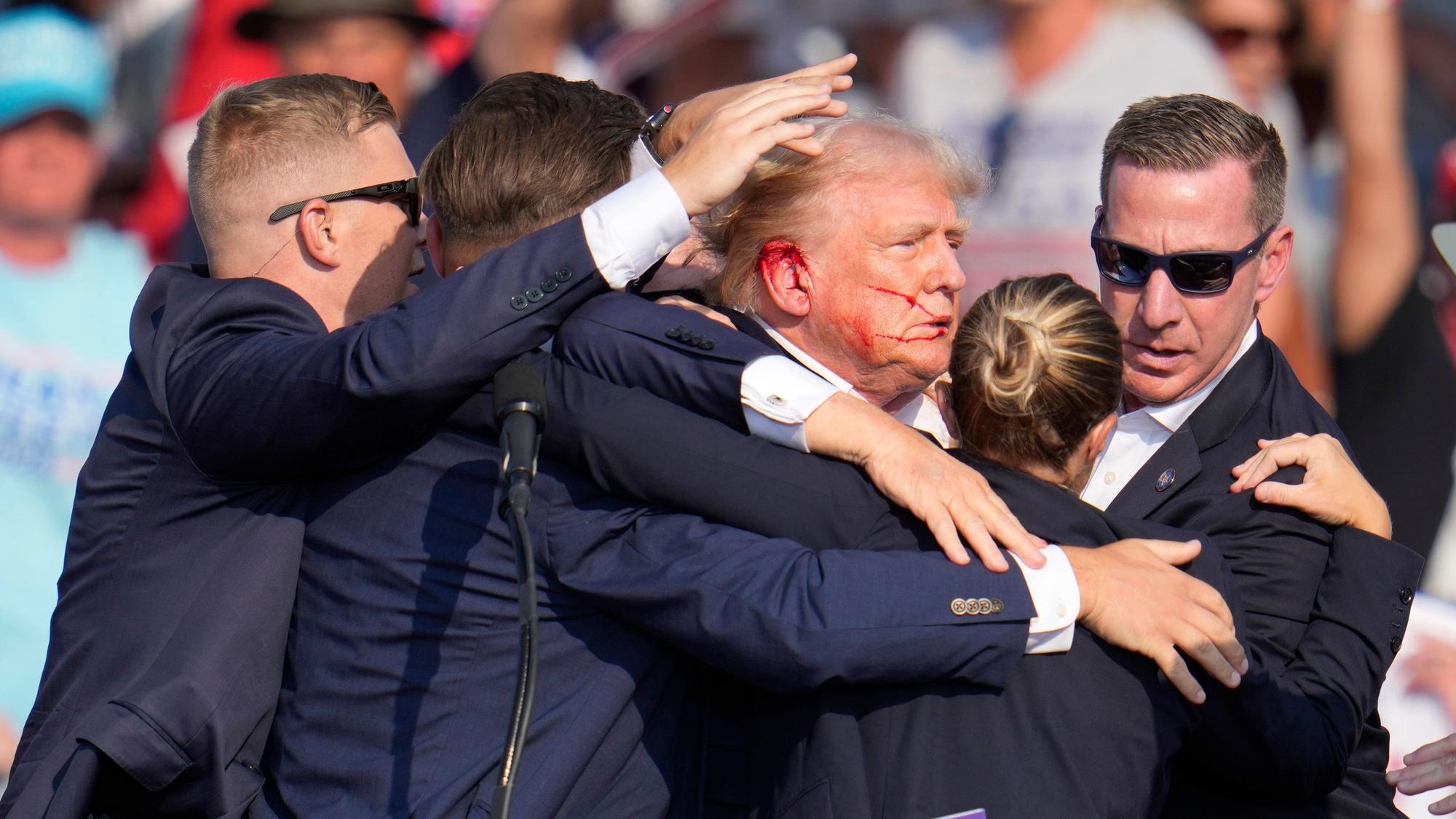 Der republikanische Präsidentschaftsbewerber und frühere US-Präsident Donald Trump wird von Agenten des US-Geheimdienstes Secret Service umringt, als ihm bei einer Wahlkampfveranstaltung von der Bühne geholfen wird.