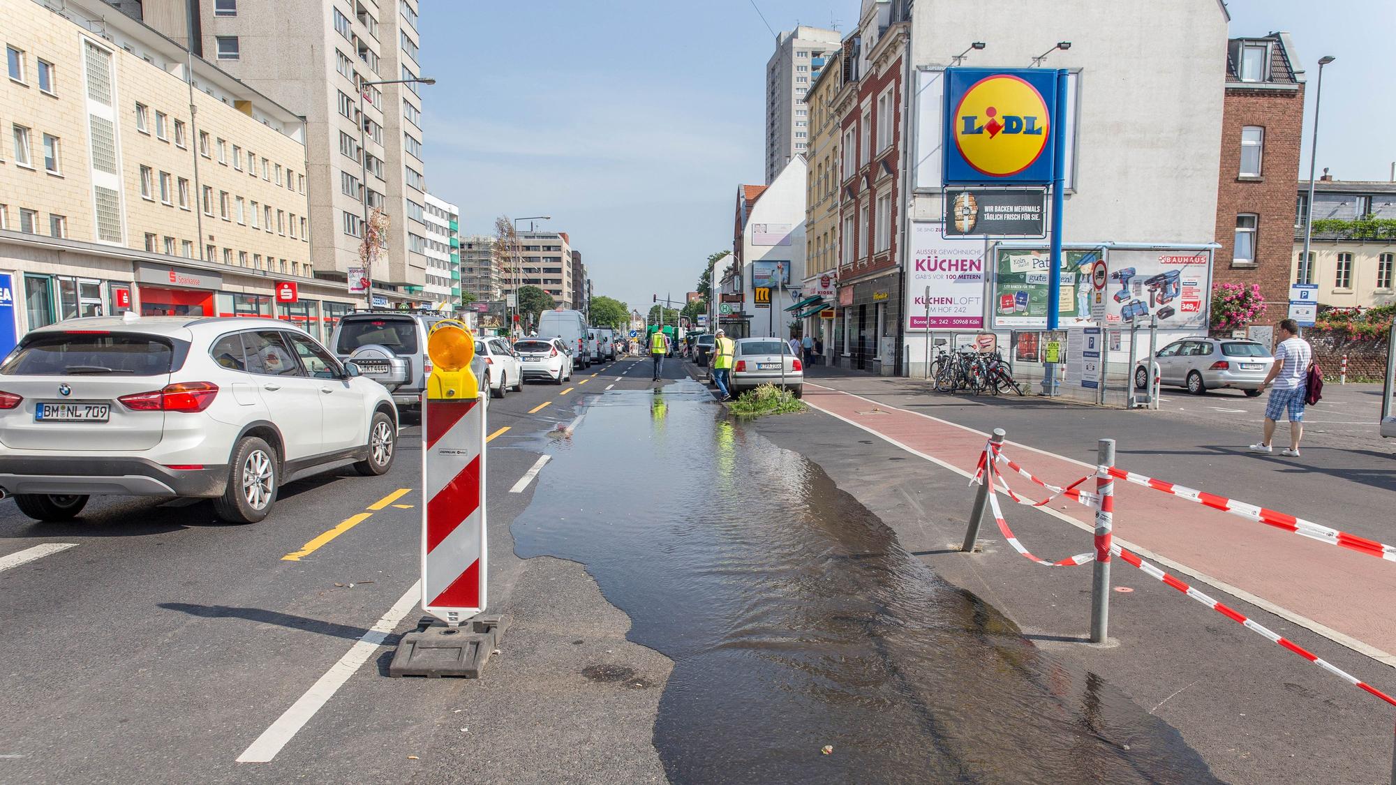 Auf einer Fahrbahn ist Wasser zu sehen, es ist auch einem Hydranten ausgetreten.