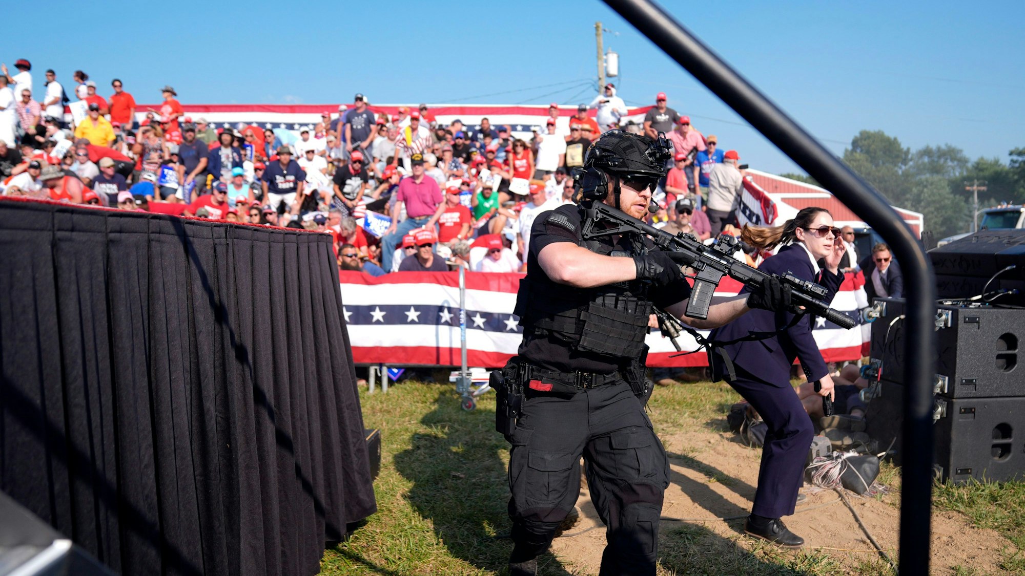 Einsatzkräfte stürmen die Bühne während einer Wahlkampfveranstaltung mit Donald Trump. Trump wurde bei einem Schusswaffenangriff auf der Bühne am Ohr verletzt. Der mutmaßliche Schütze wurde von Sicherheitskräften getötet.