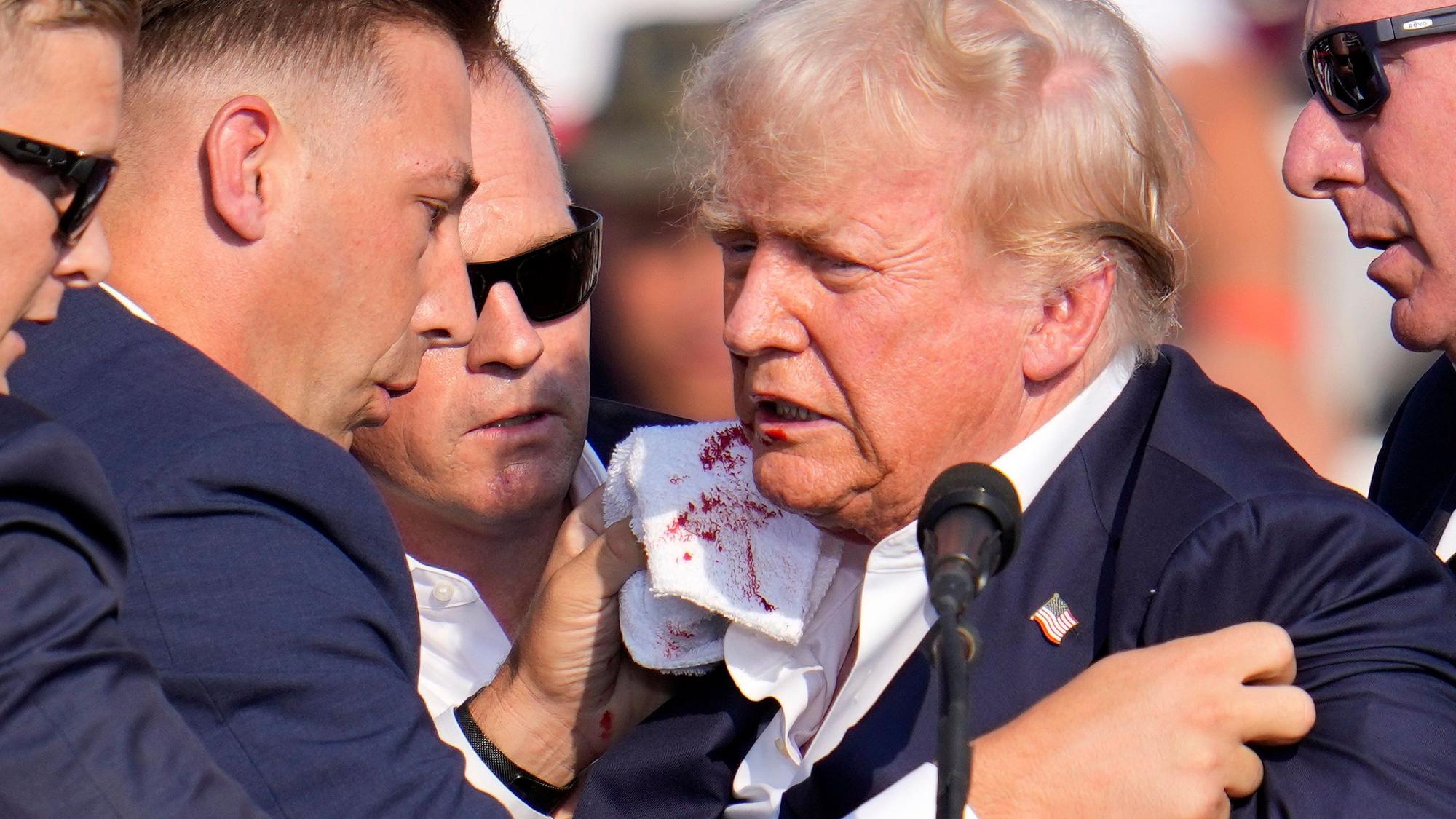 Der ehemalige US-Präsident Donald Trump ist bei einer Wahlkampfveranstaltung in Butler im US-Bundesstaat Pennsylvania von einem Schuss des Attentäters am rechten Ohr getroffen worden. Der Secret Service stürmt auf ihn zu und drückt den 78-Jährigen nach unten.
