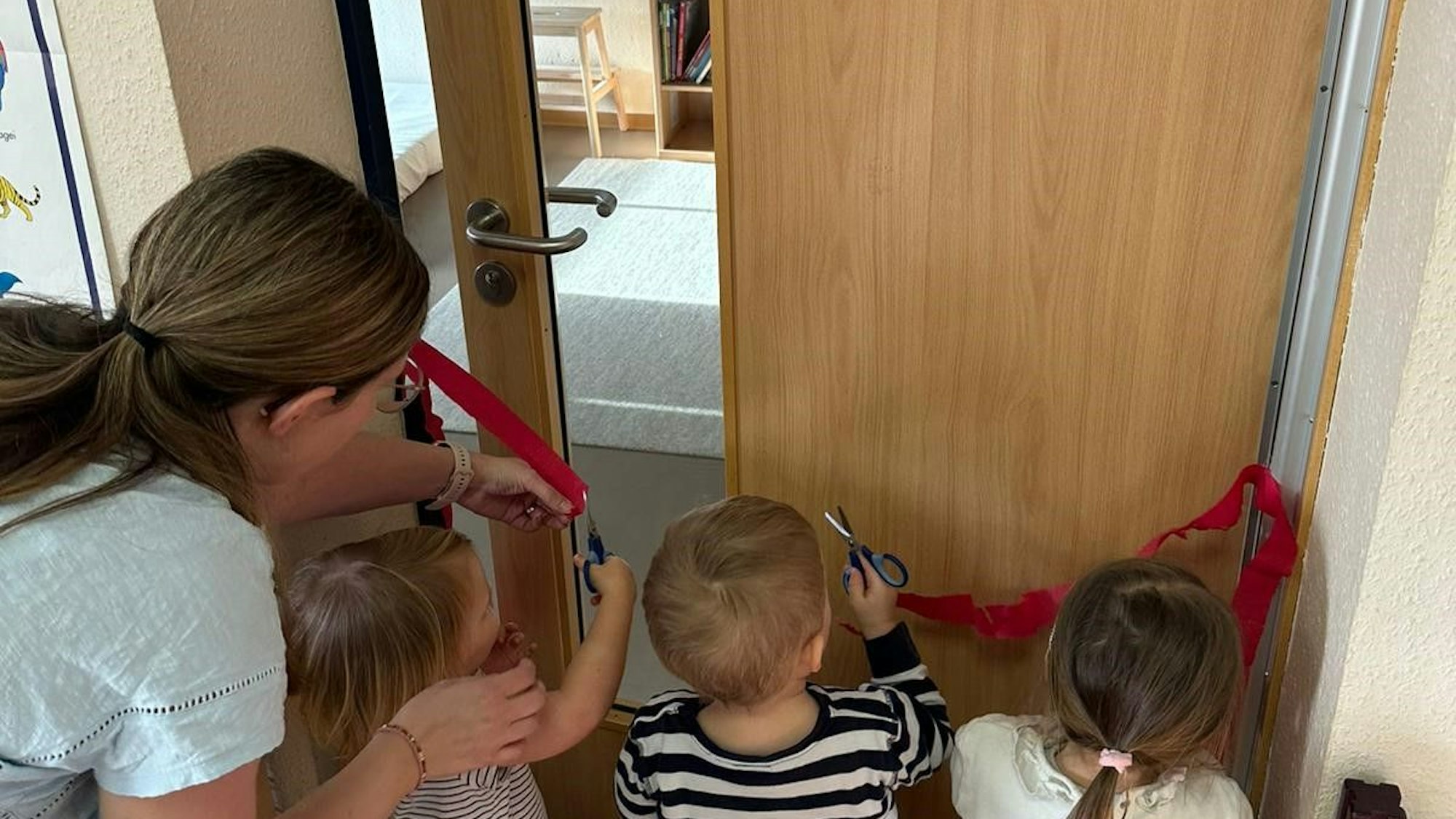 Kinder durchschneiden in Bornheim ein Band an der Tür zur neuen Bib.