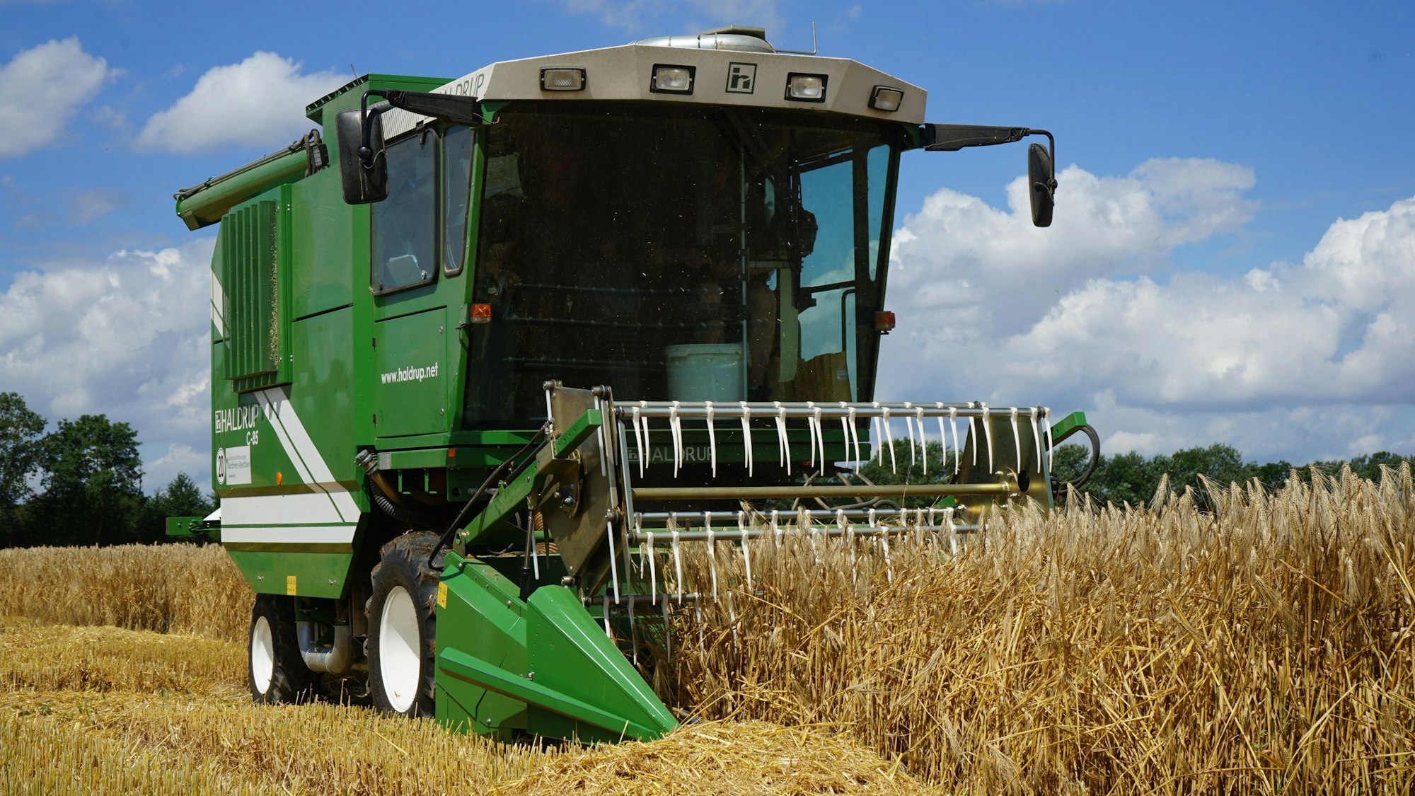 Ein Mähdrescher fährt über ein Feld.