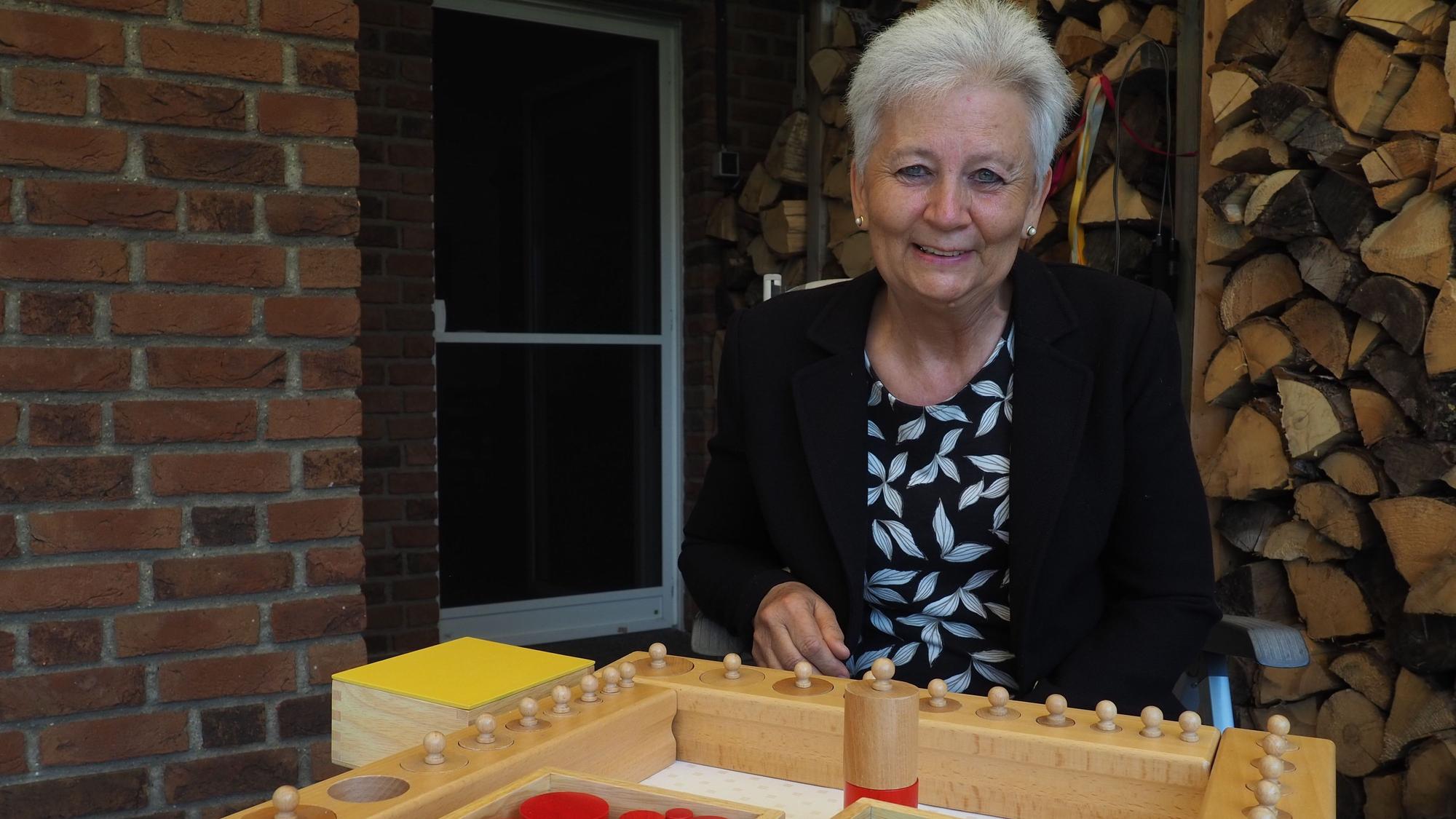 Ilona Raabe sitzt hinter einem hölzernen Montessori-Spielzeug.