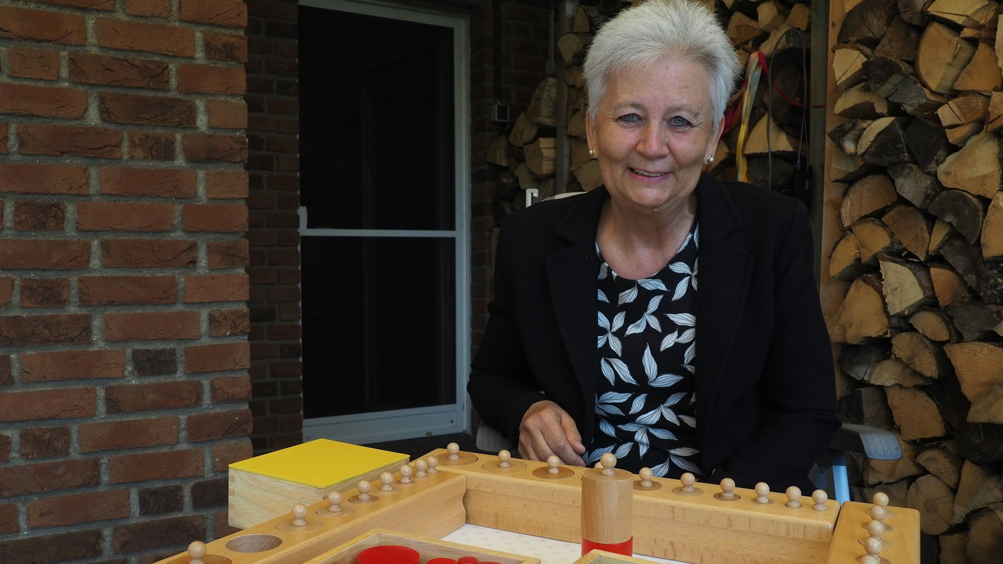 Ilona Raabe sitzt hinter einem hölzernen Montessori-Spielzeug.