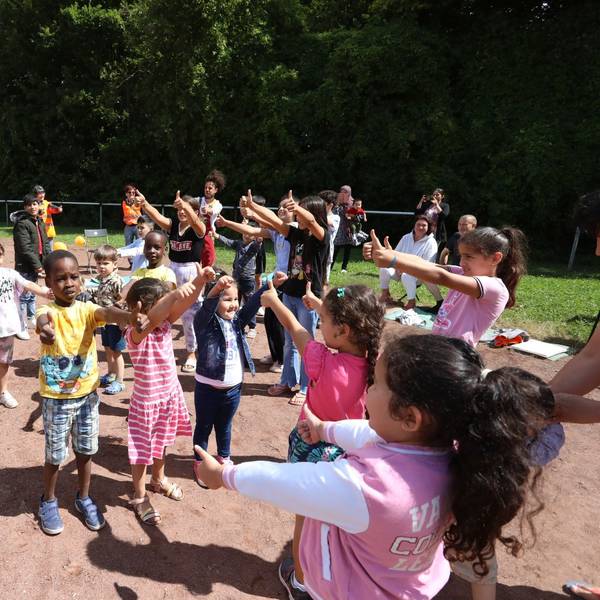 Eine Gruppe von Kindern mit zwei Clowns auf einem Sportplatz.