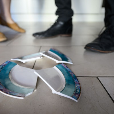 Ein Mann und eine Frau stehen hinter einem zerbrochenen Teller in einer Küche.