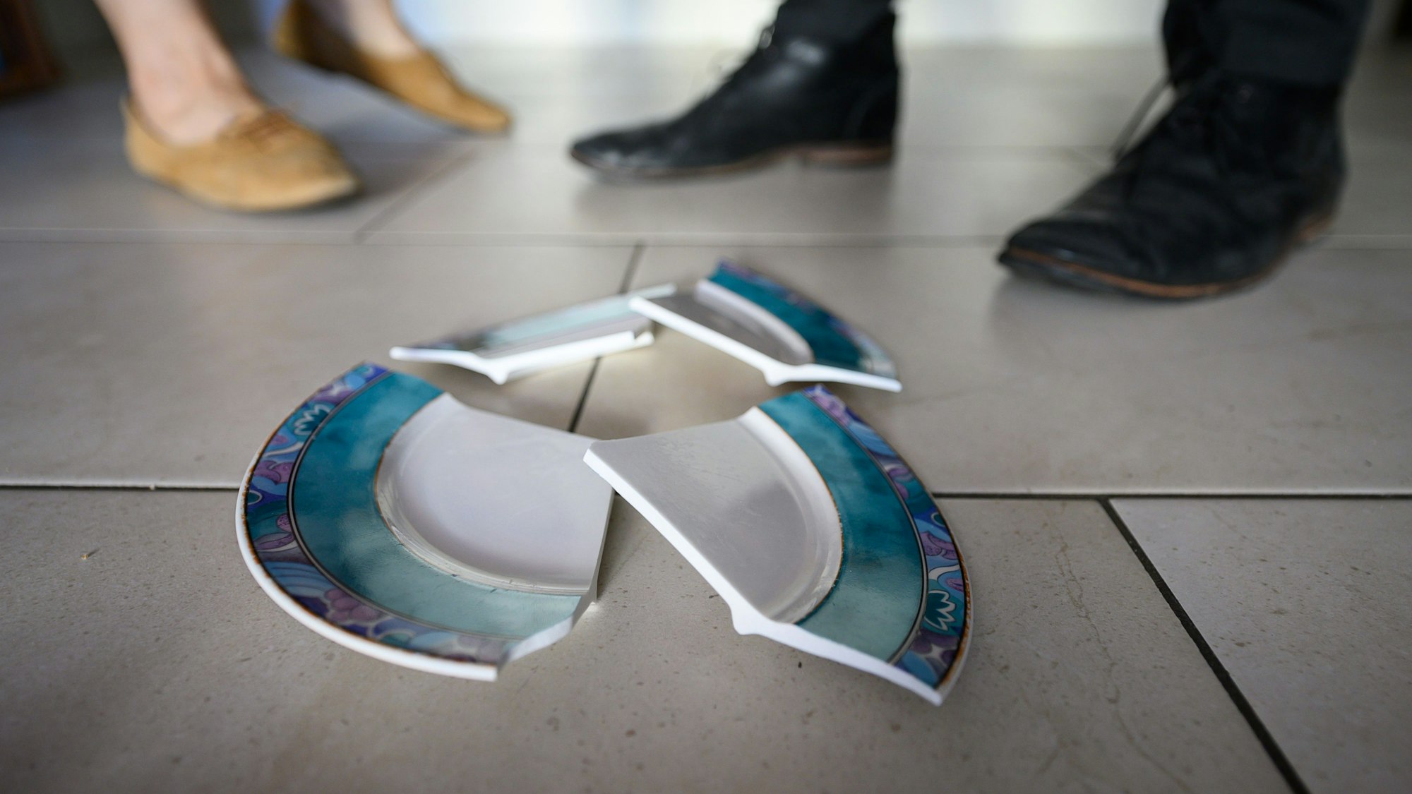 Ein Mann und eine Frau stehen hinter einem zerbrochenen Teller in einer Küche.