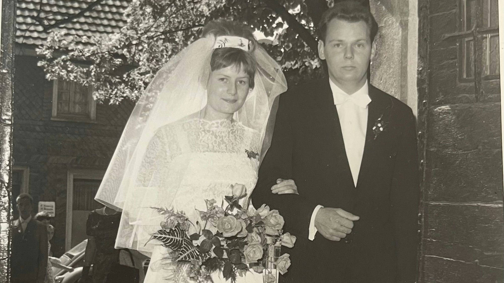 Ein altes schwarz-weißes Hochzeitsfoto eines Paares, das in die Kirche läuft.