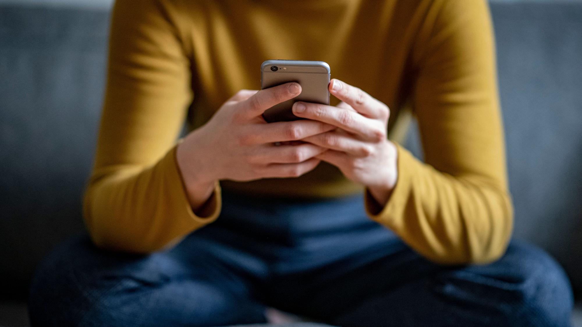 ARCHIV - 24.04.2021, Berlin: ILLUSTRATION - Eine junge Frau hält ein Smartphone in der Hand. (gestellte Szene) (zu dpa: «Umfrage: Smartphone-Nebenwirkungen von Ablenkung bis Schmerzen») Foto: Fabian Sommer/dpa +++ dpa-Bildfunk +++