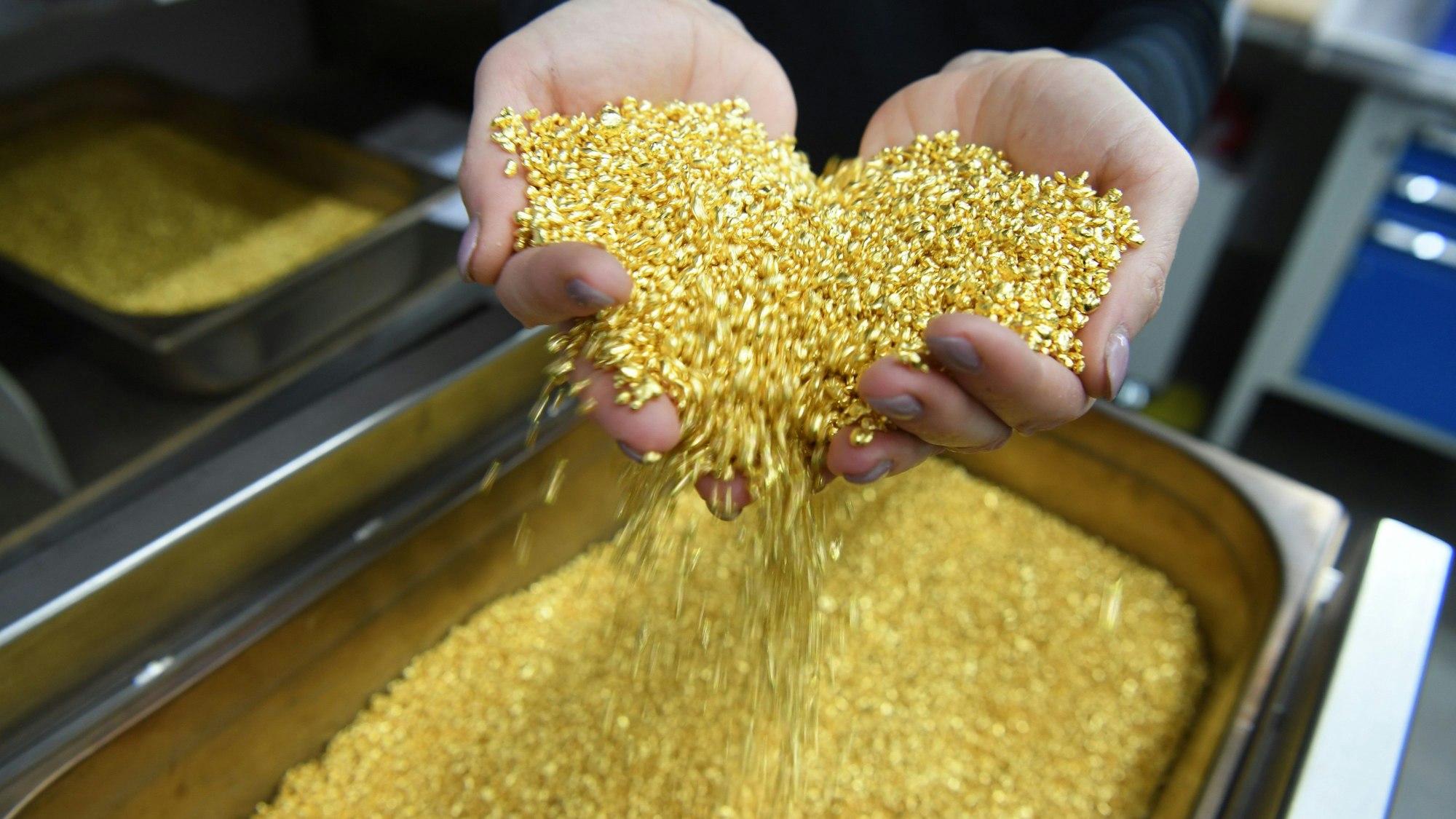 ARCHIV - 28.04.2017, Baden-Württemberg, Pforzheim: Goldgranulat, das einen Feingoldgehalt von 99,99 Prozent hat, rieselt bei der Firma Allgemeine Gold- und Silberscheideanstalt AG Agosi in Pforzheim (Baden-Württemberg) durch zwei Hände. In Köln ist Goldgranulat im Wert von einer Million Euro gestohlen worden. (zu dpa: «Gold-Diebstahl am Kölner Flughafen: Gesuchter Mann ermittelt») Foto: Uli Deck/dpa +++ dpa-Bildfunk +++