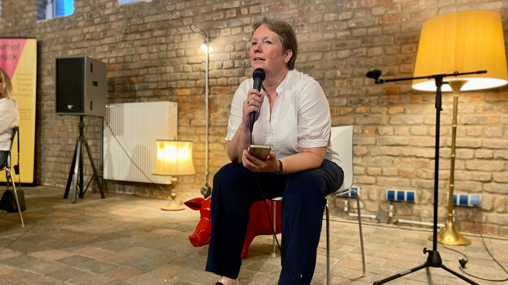 Anne Klöters sitzt auf einem Stuhl und trägt Gedichte vor.