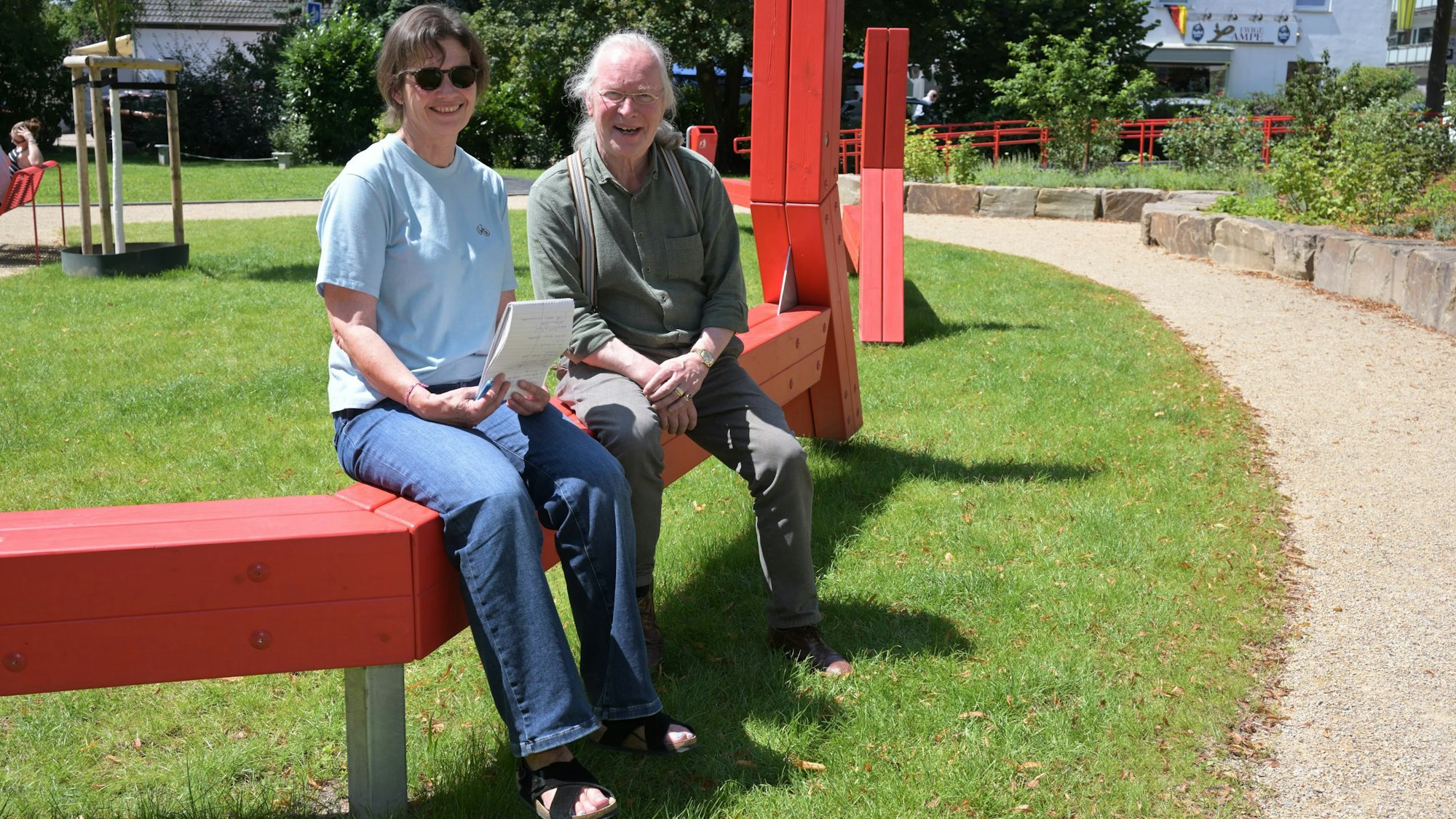Beide sitzen auf einer roten Balancierstange.