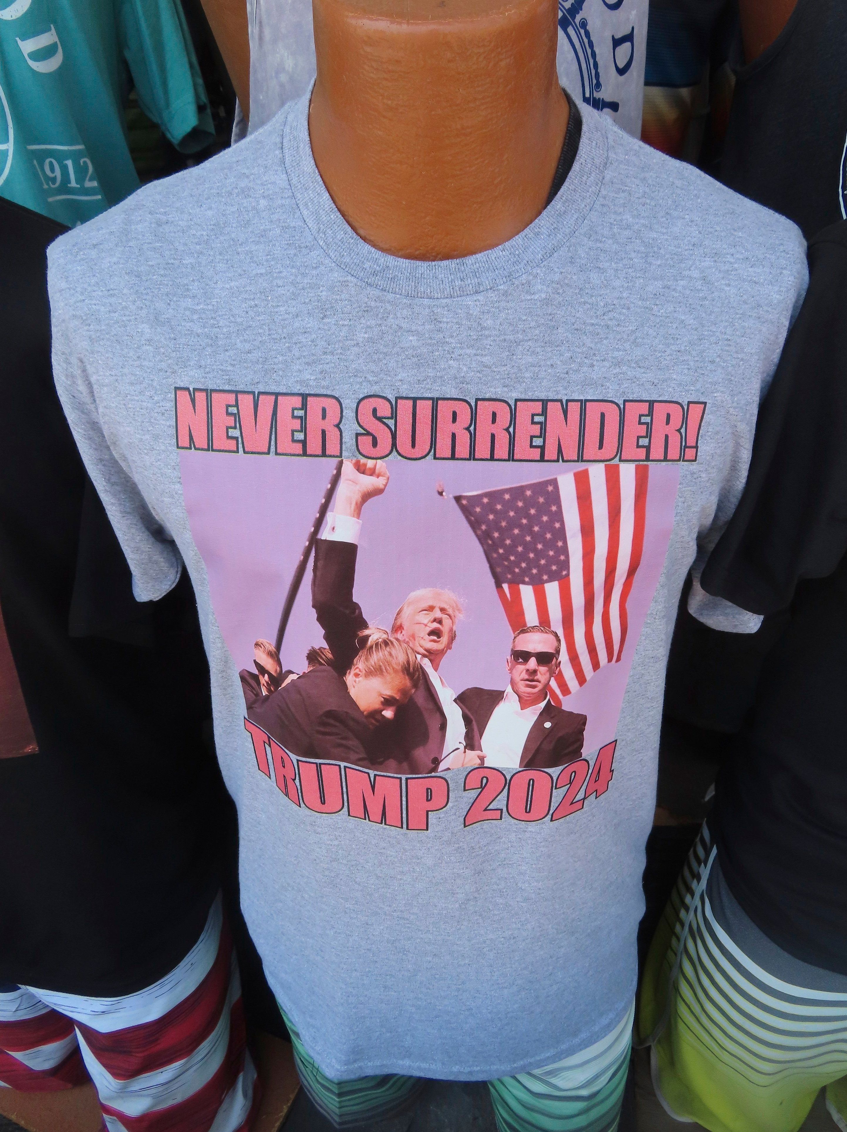 15.07.2024, USA, Wildwood: T-Shirts, die sich auf das Attentat auf den ehemaligen US-Präsidenten Donald Trump beziehen, fanden am 15. Juli 2024, weniger als 48 Stunden nach dem Vorfall, auf der Strandpromenade in Wildwood, N.J., reißenden Absatz. Foto: Wayne Parry/AP +++ dpa-Bildfunk +++