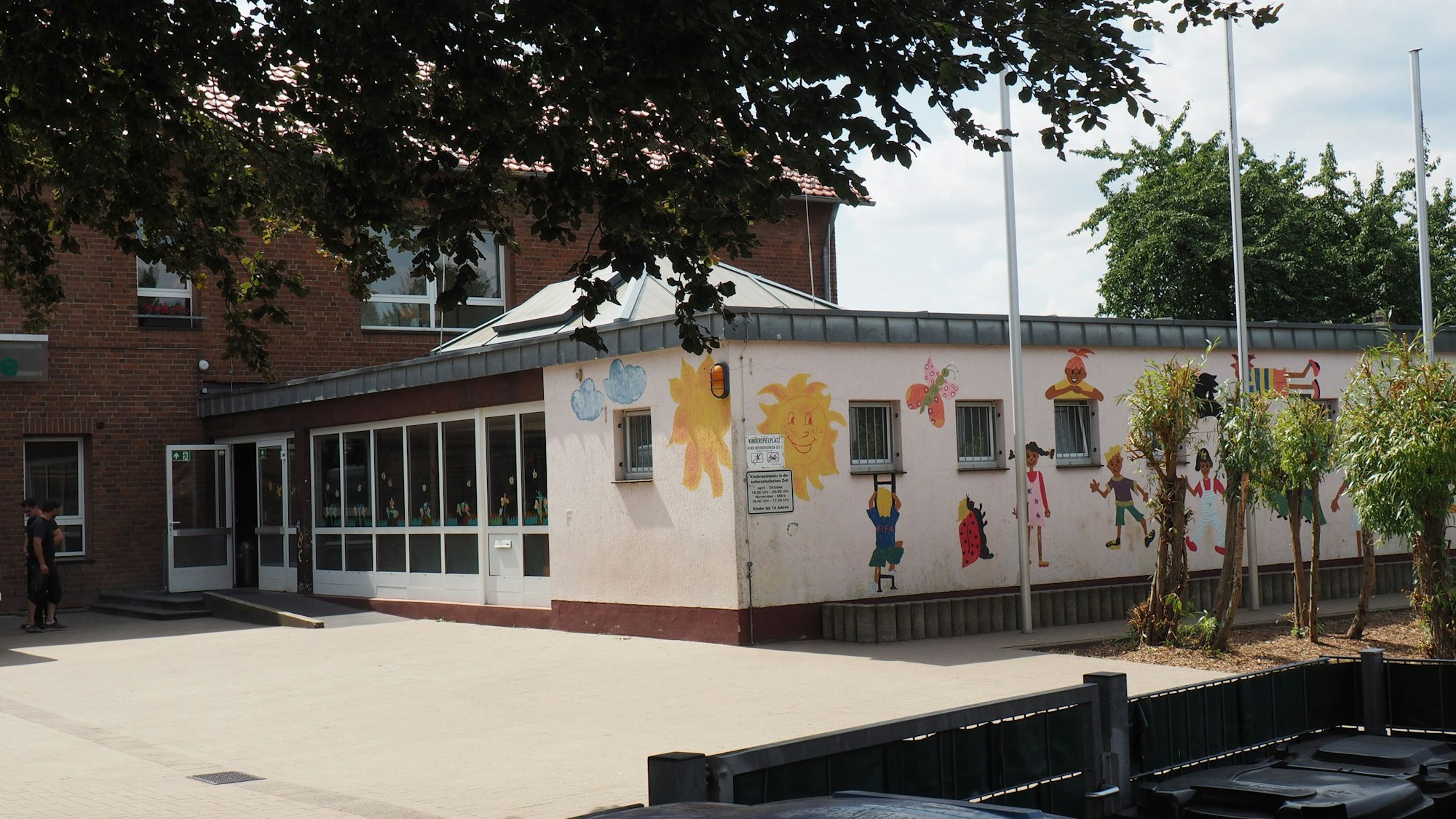 Ein eingeschossiges Gebäude, die Fassade weiß, an einigen Stellen ist sie bemalt.