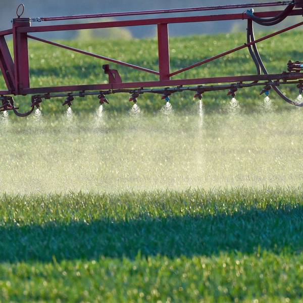 Ein Landwirt fährt mit einer Dünger- und Pestizidspritze über ein Feld.