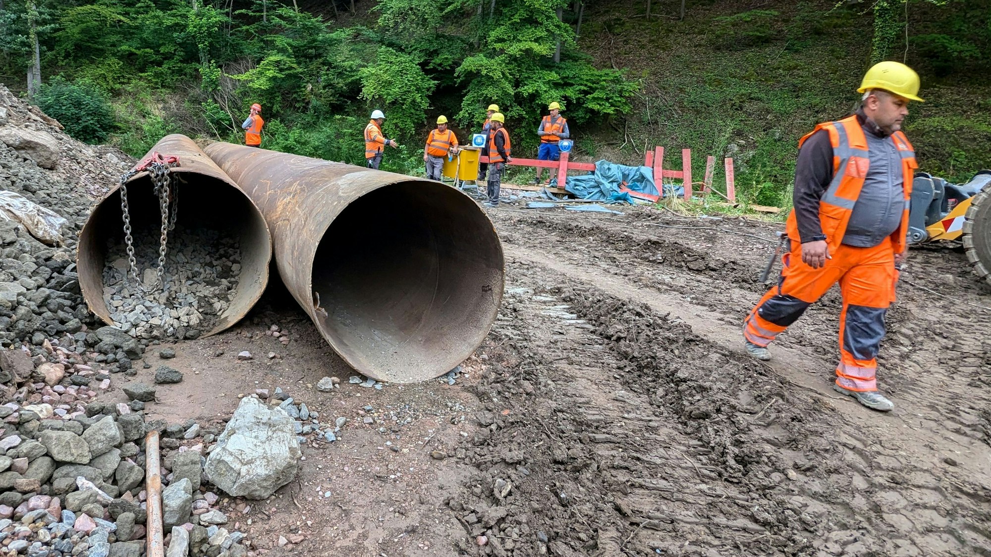 Ein Bauarbeiter geht an zwei großen Stahlröhren vorbei.