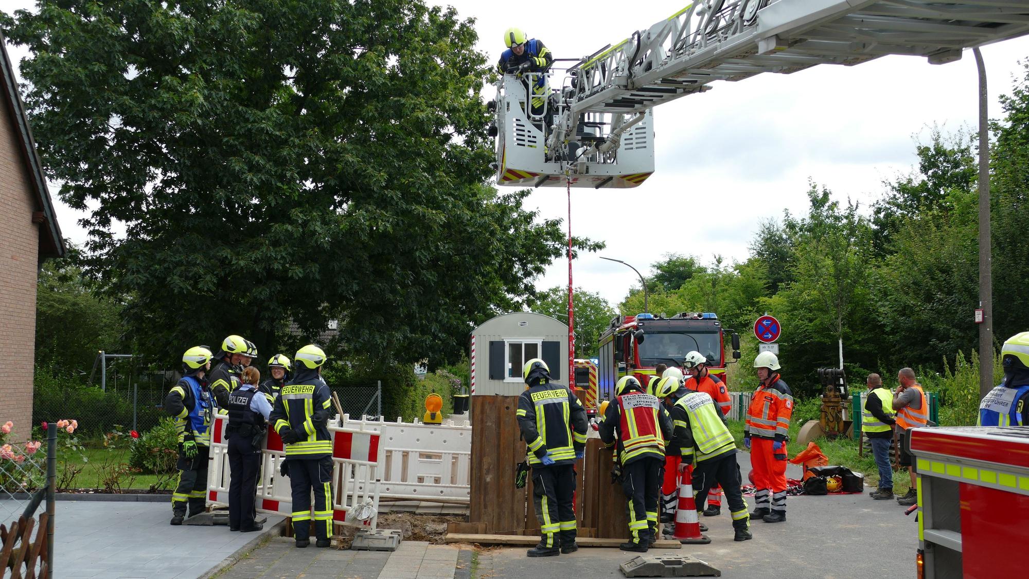 Feuerwehrleute stehen um eine Baugrube herum.