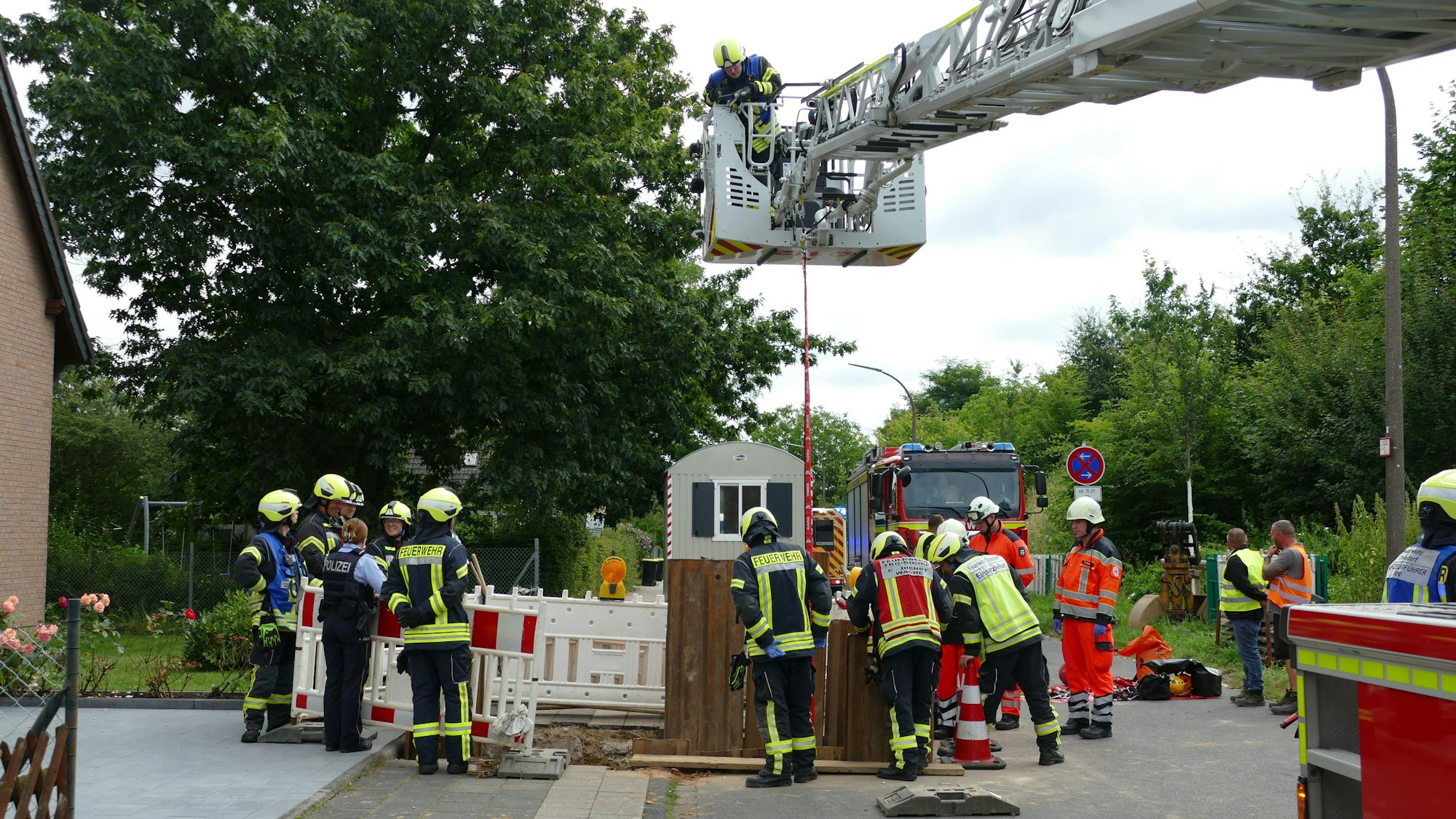 Feuerwehrleute stehen um eine Baugrube herum.