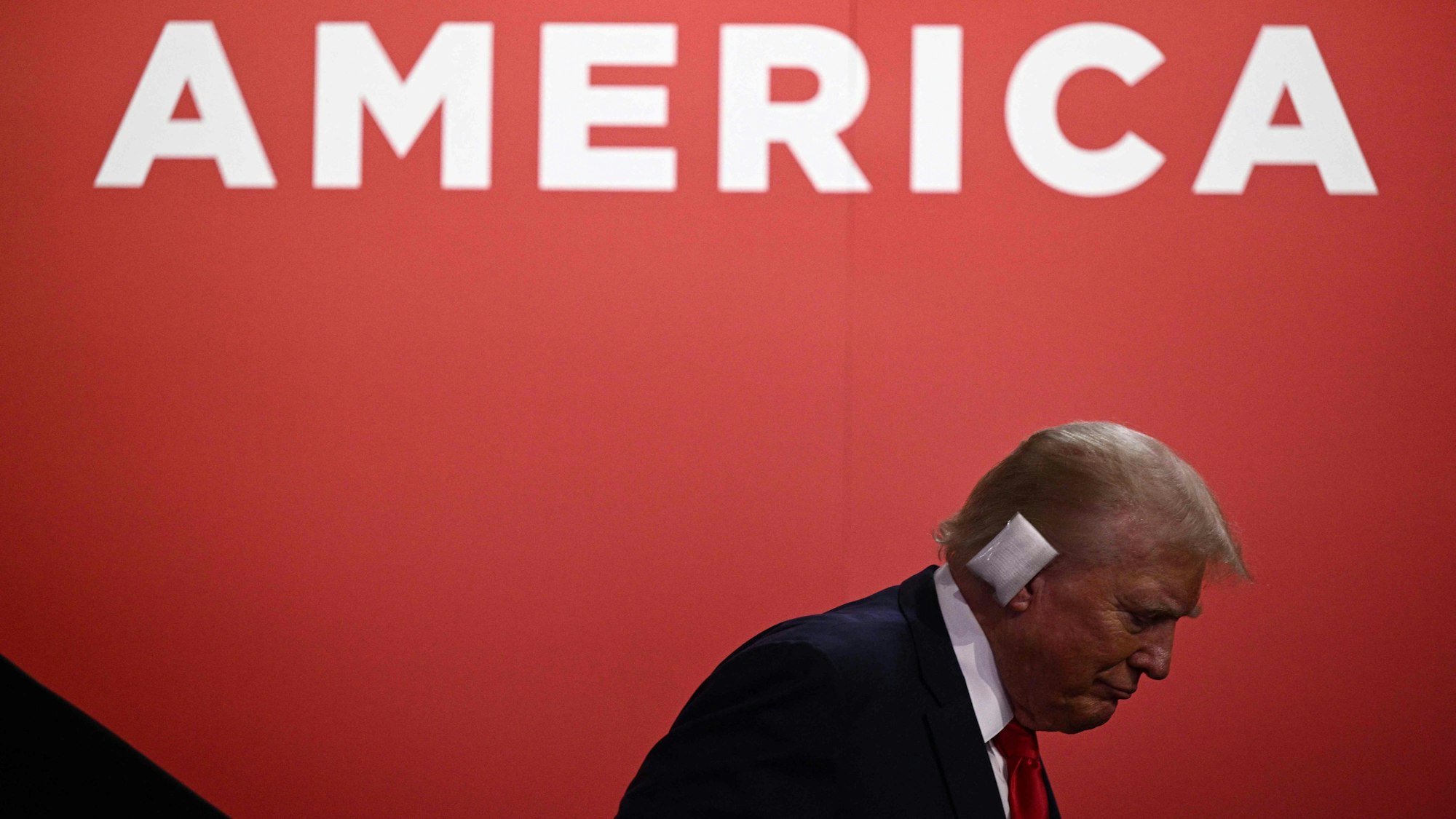 Donald Trump steht vor dem Schriftzug „America“