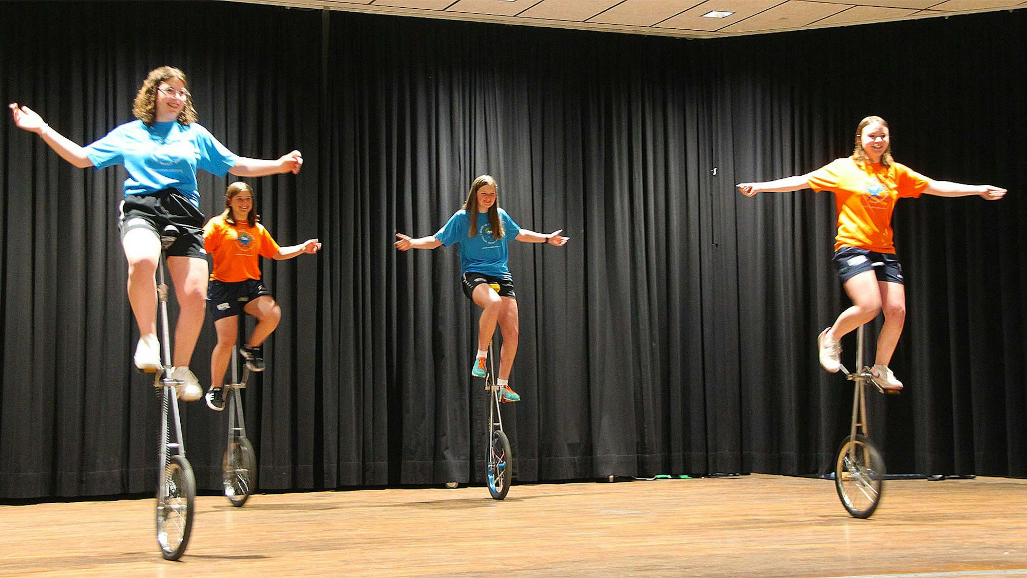 Vier junge Frauen fahren mit Einrädern auf einer Bühne.