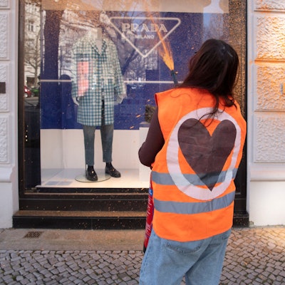 Eine Aktivistin der Umweltschutzgruppe Letzte Generation besprüht eine Fassade eines Luxusgeschäftes am Kurfürstendamm.