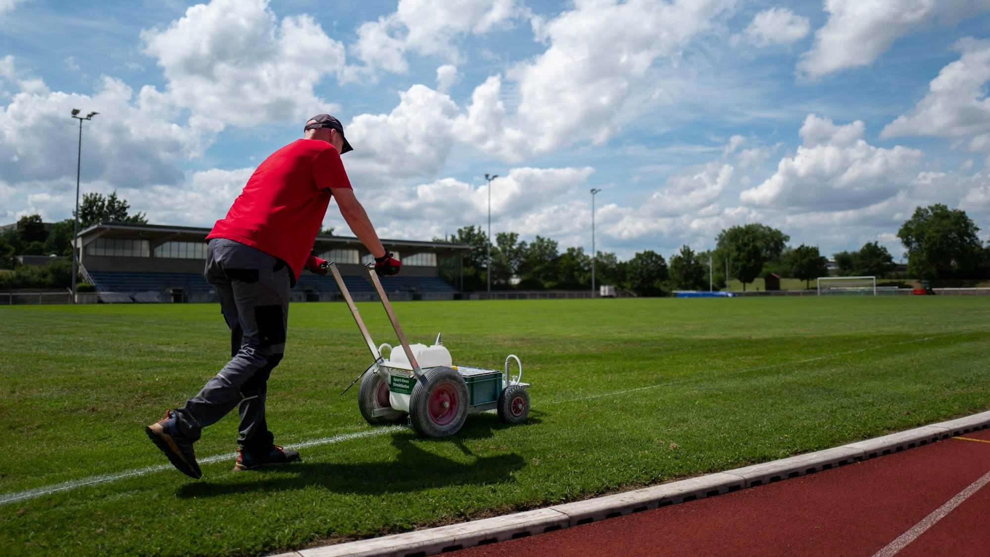 Das Bild zeigt einen städtischen Mitarbeiter, der die Seitenlinie im Erftstadion markiert.
