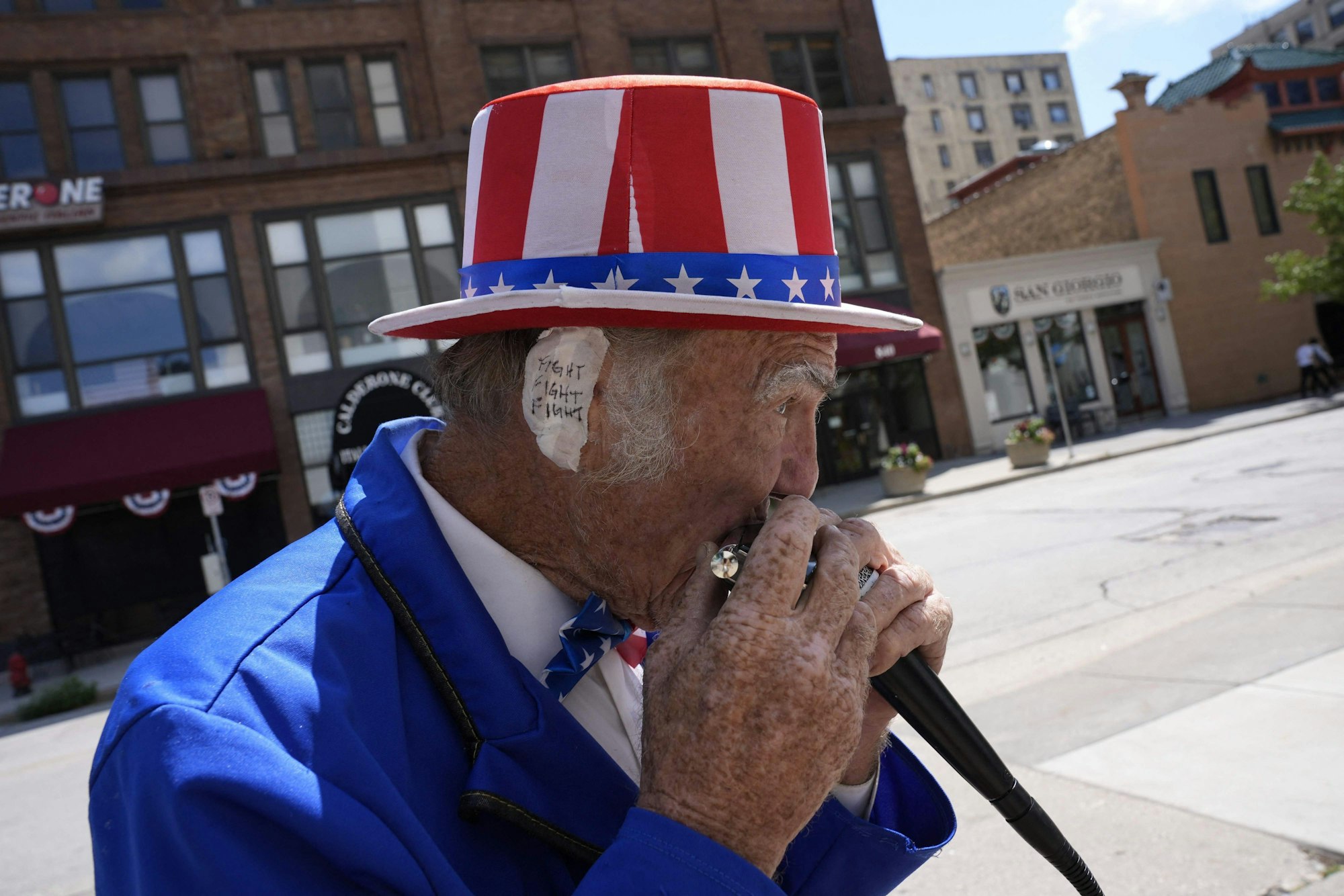 TOPSHOT - Duane Schwingel, dressed as Uncle Sam, plays harmonica outside the Fiserv Forum during the third day of the 2024 Republican National Convention in Milwaukee, Wisconsin, on July 17, 2024. Days after he survived an assassination attempt Donald Trump won formal nomination as the Republican presidential candidate and picked Ohio US Senator J.D. Vance for running mate. (Photo by Nick Oxford / AFP)