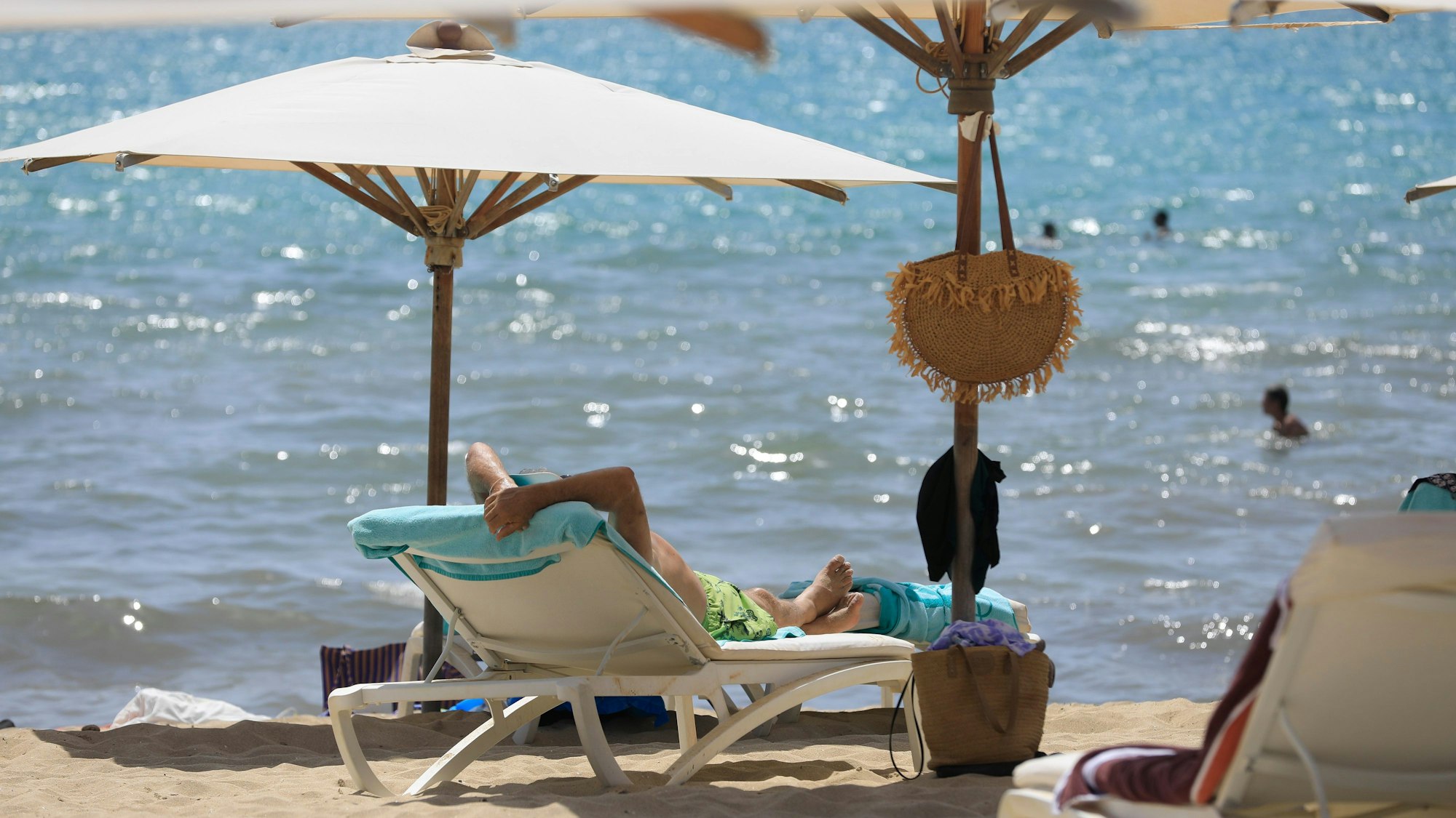 17.07.2024, Spanien, Palma: Menschen sonnen sich am Strand von Arenal und baden im Meer an einem warmen Sommertag. Foto: Clara Margais/dpa +++ dpa-Bildfunk +++