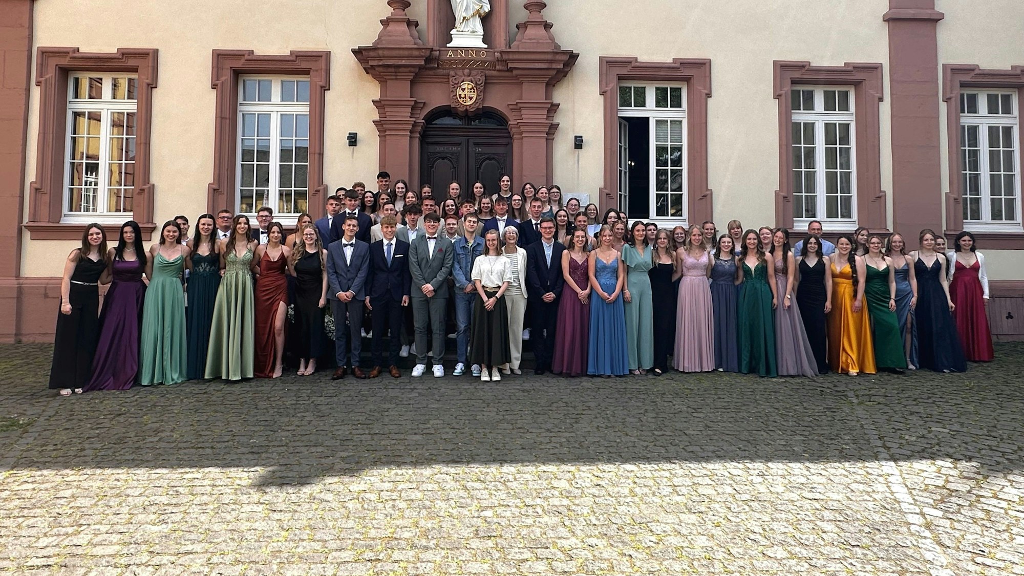 Der Abiturjahrgang 2024 steht in Abendgaderobe vor dem Schulgebäude des Hermann-Josef-Kollegs in Steinfeld.