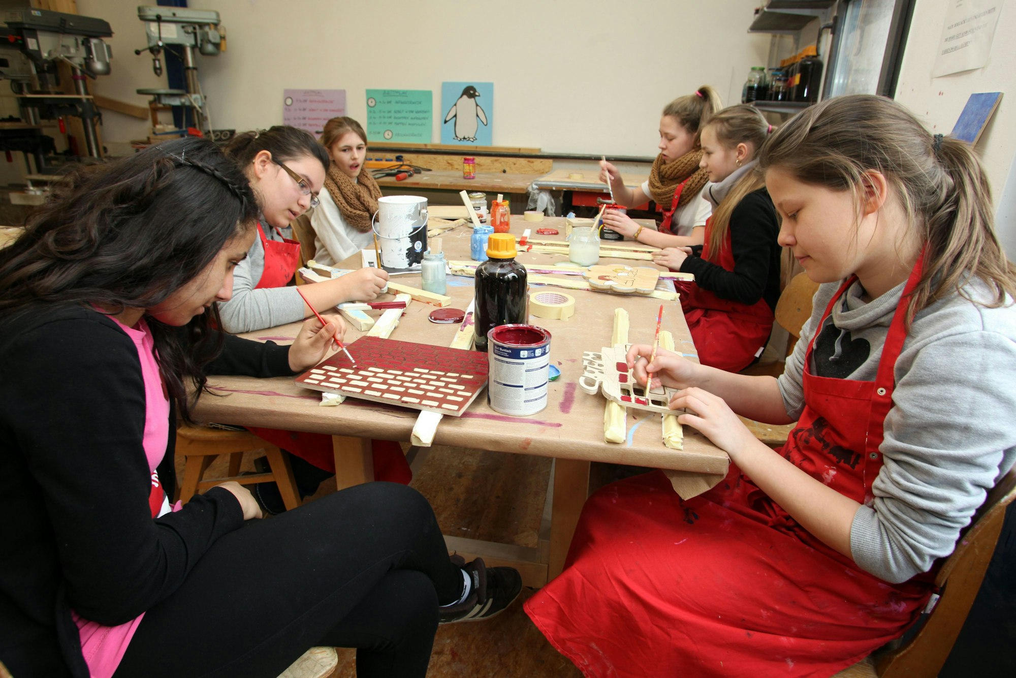 Junge Frauen sitzen an einem Tisch und malen mit Pinseln.