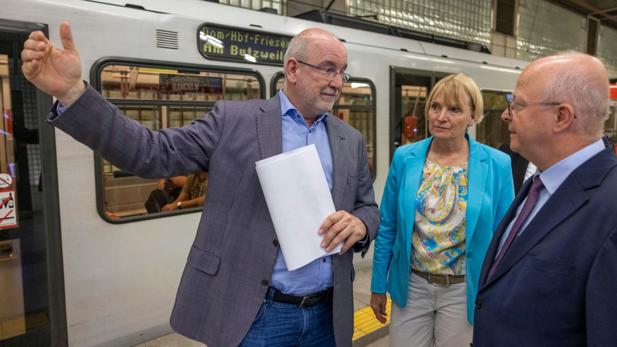 Zwei Männer und eine Frau stehen neben einer Straßenbahn