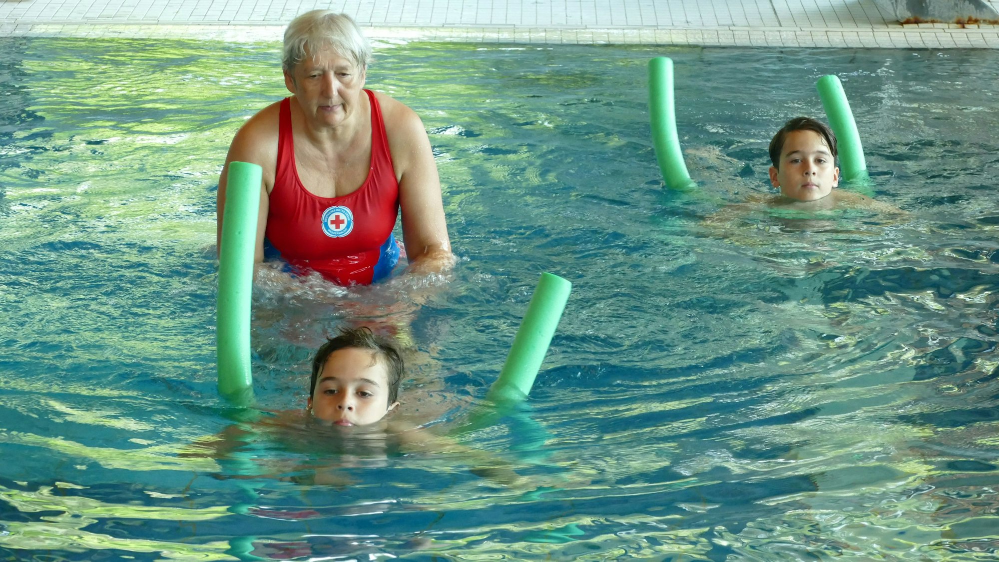 Eine Frau bringt zwei Jungs Schwimmen bei.