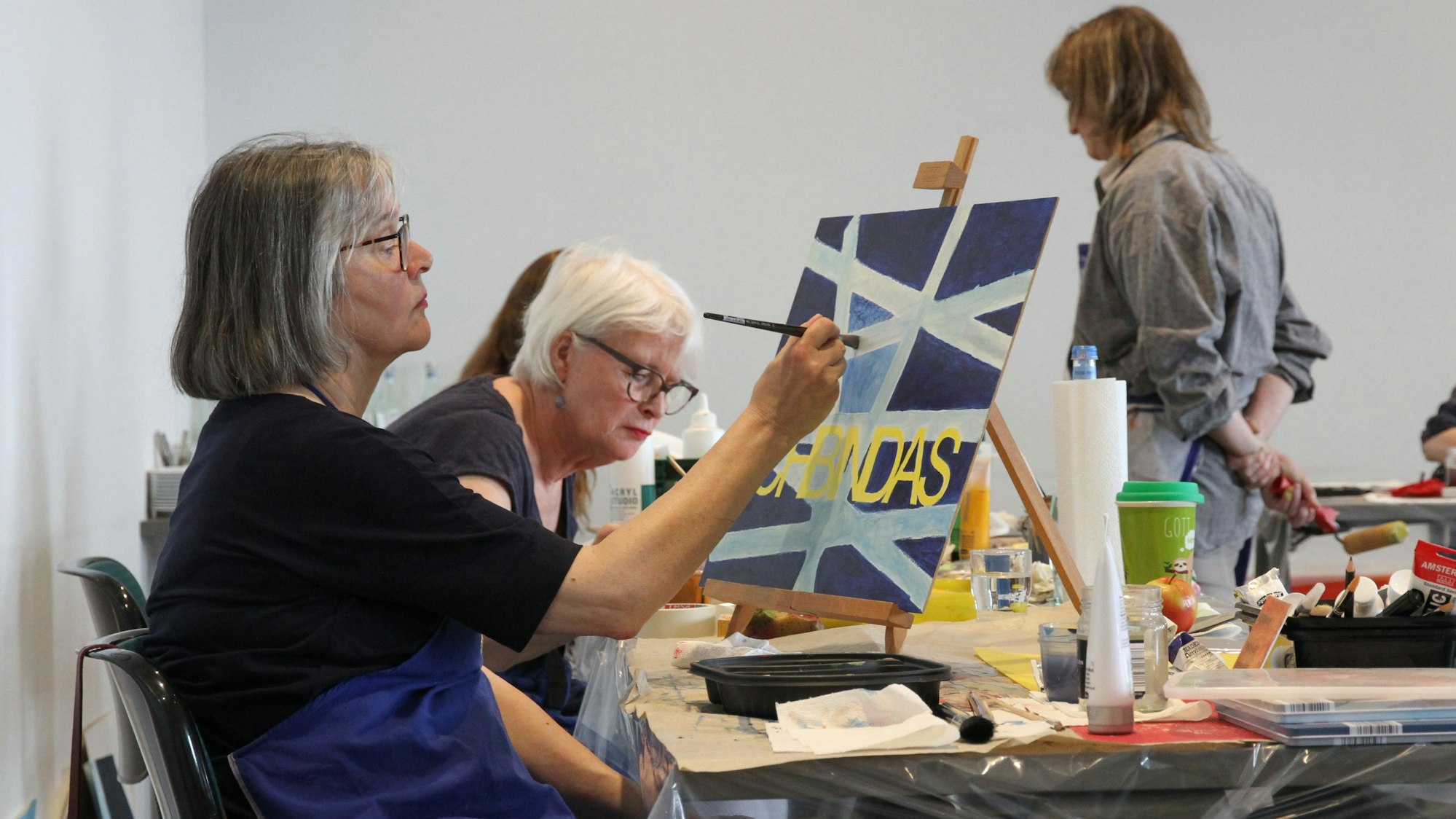 Eine Frau arbeitet an einer Malstaffelei auf einem Tisch