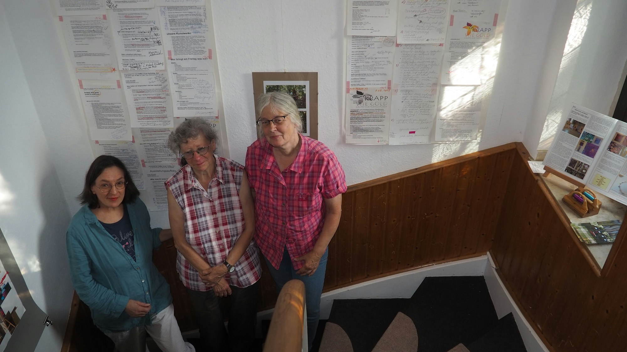 Die drei Frauen stehen nebeneinander auf einer Treppe.