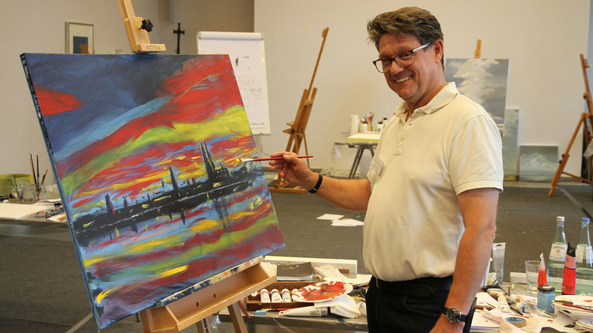 Ein Mann an einer Staffelei mit einer Ansicht von Köln