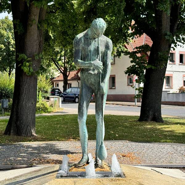 Zu sehen ist ein Brunnen in der Form eines Glasbläsers.