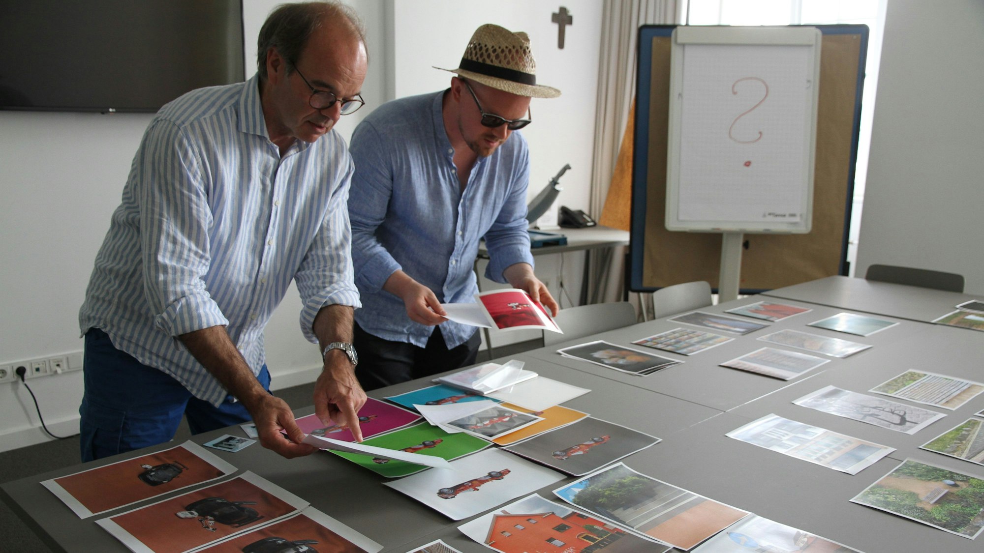 Zwei Männer beugen sich über einen Tisch mit Fotografien