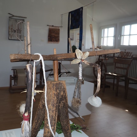 Das Bild zeigt einen Ausstellungsraum des Museums, im Vordergrund ein Objekt, das überwiegend aus Holz besteht.