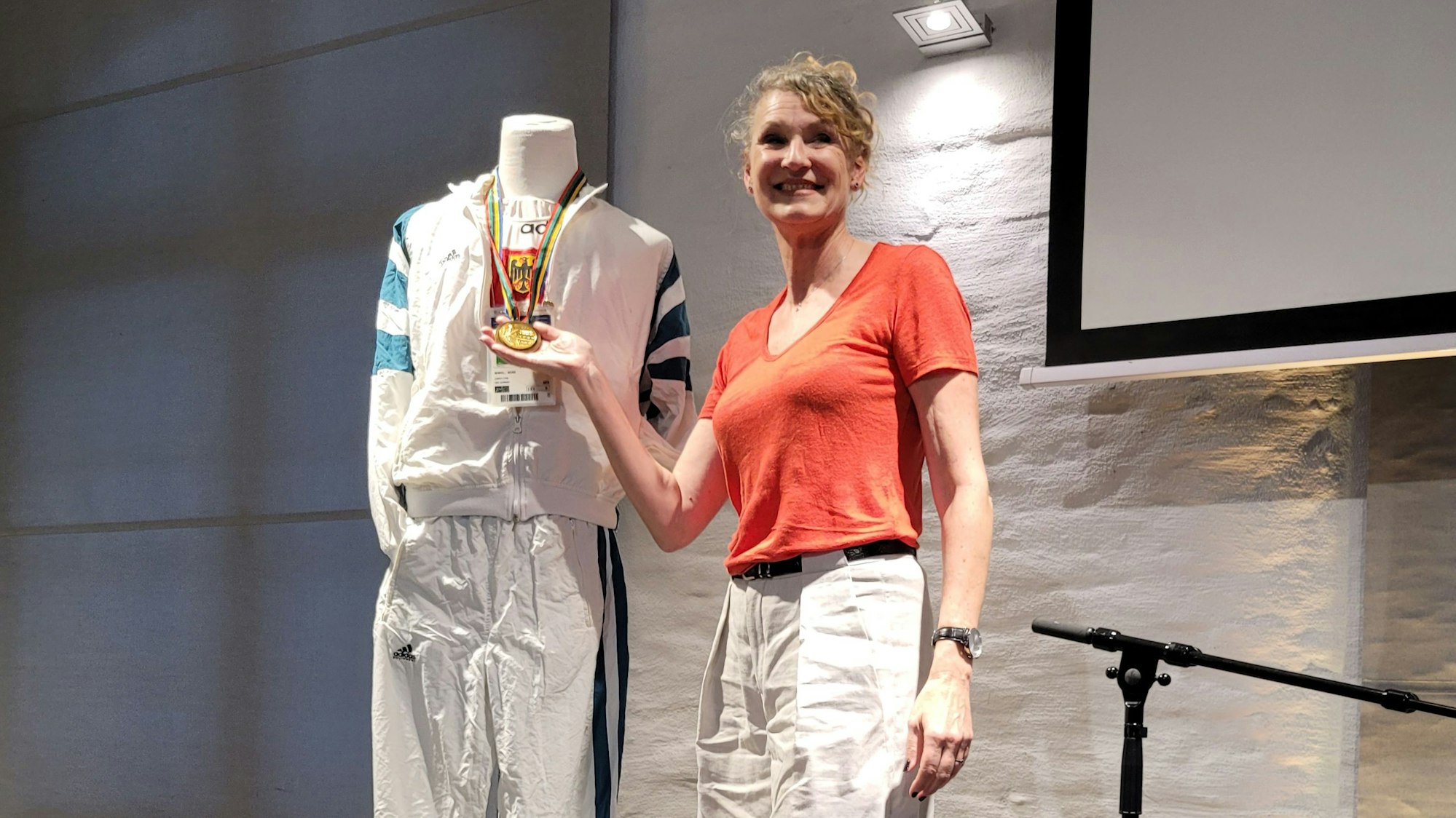 Eine Frau hält eine Goldmedaille in der Hand.