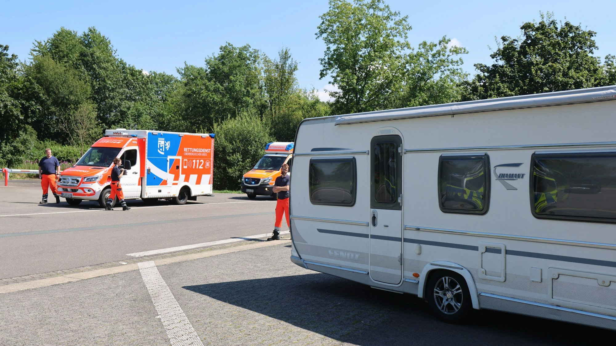 Mehrere Rettungssanitäter stehen an einem Wohnwagen.