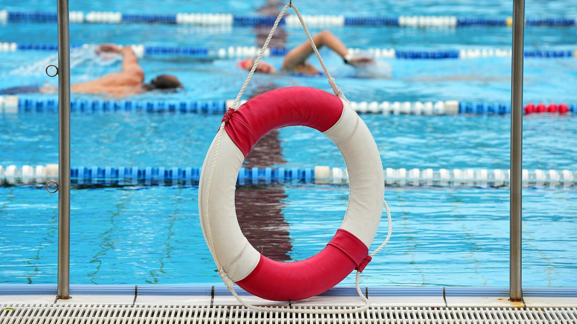 Ein Rettungsring hängt in einem Freibad am Rand des Beckens.